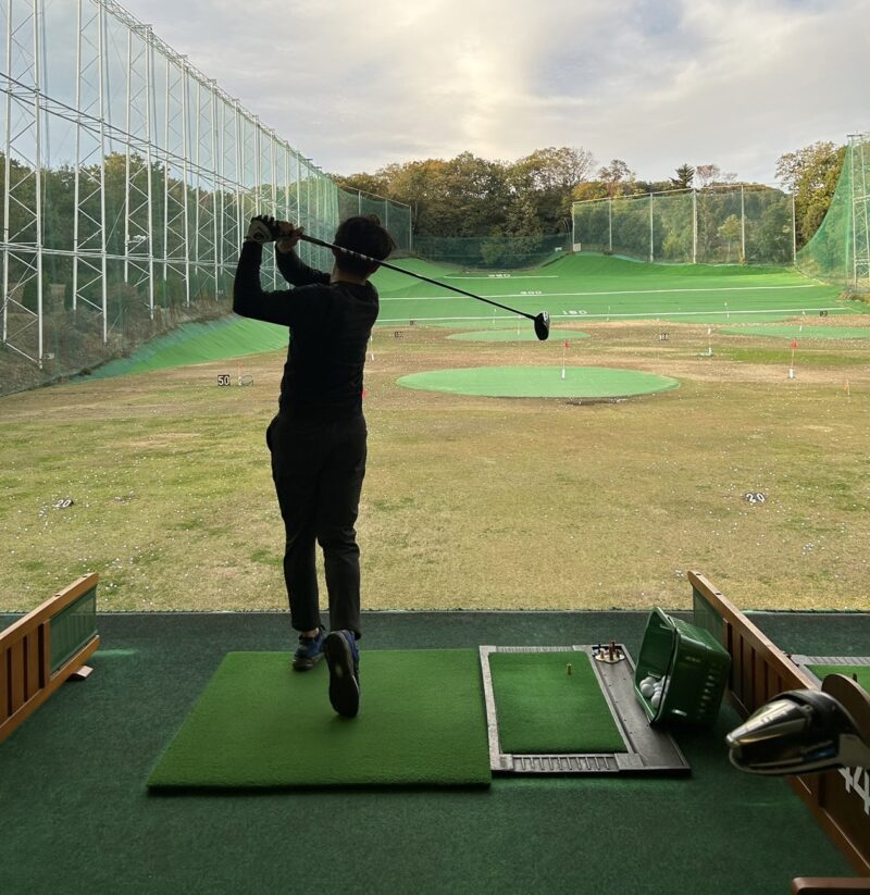 屋外練習場でドライバーを振り抜くゴルファー